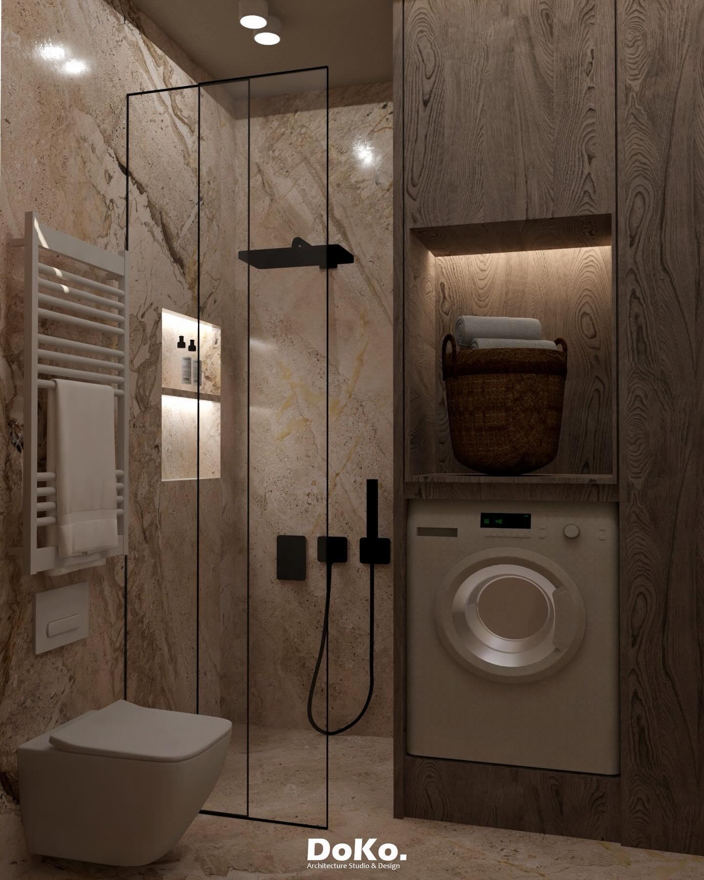 Toilet kompakt me mermer të ngrohtë: dush me xham, rubineti të zeza, kamare e ndriçuar dhe lavatriçe e integruar.